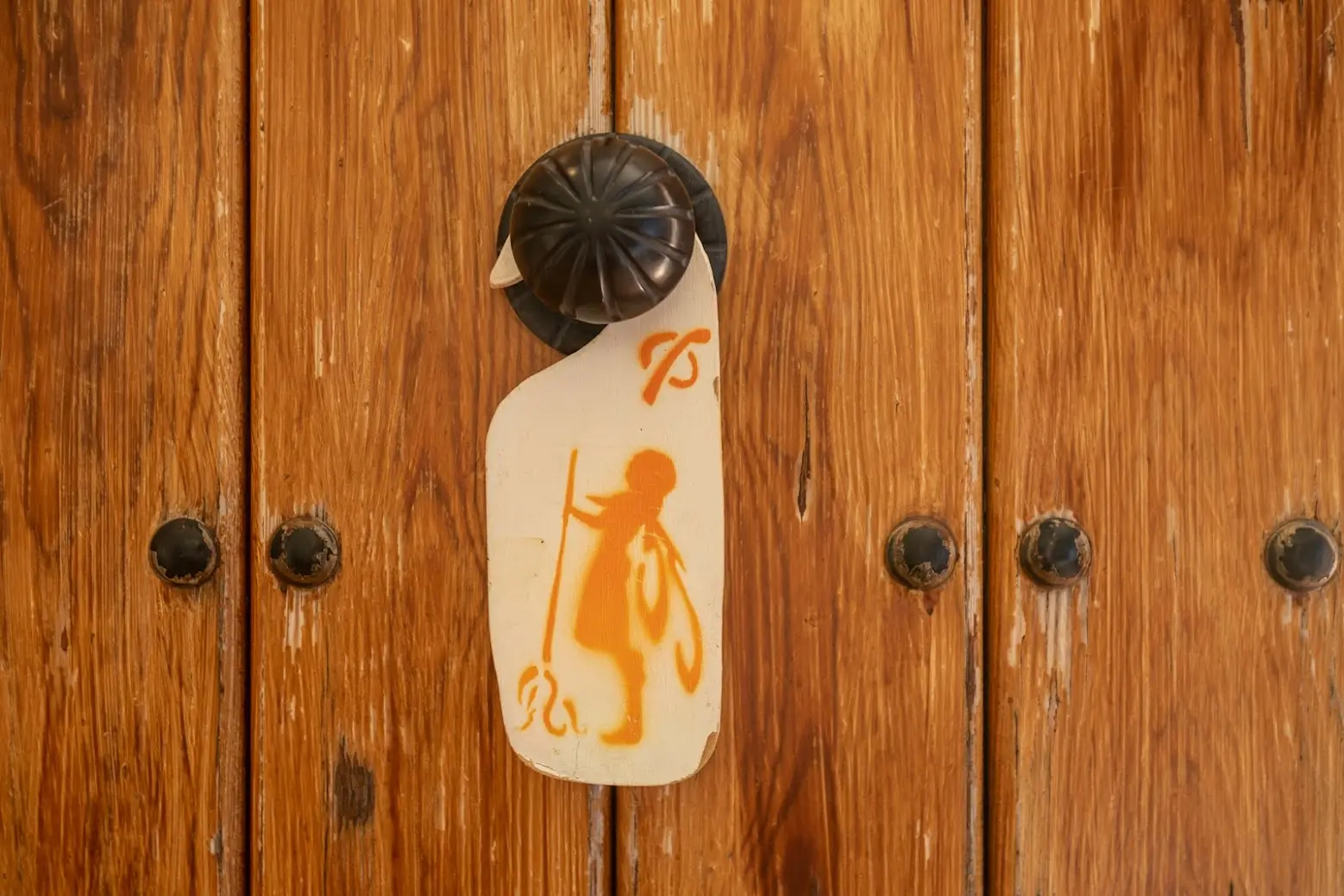 Detalle del servicio de limpieza con colgador artesanal en puerta de madera